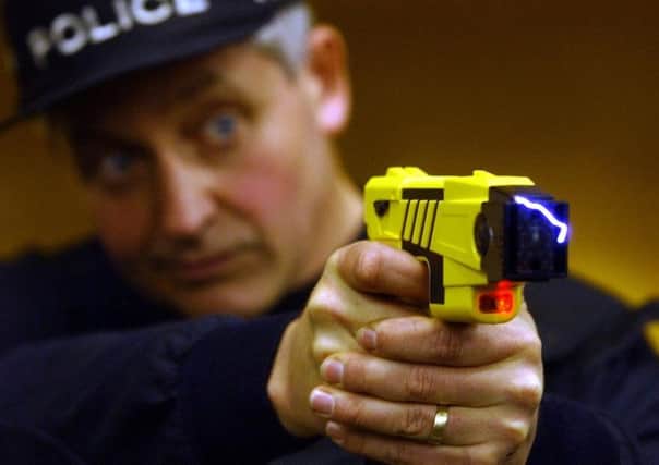 A police officer demonstrates the firing of taser gun, which delivers an electric shock to stun a suspect