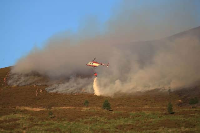 A helicopter drops water as firefighters tackle the wildfire on Saddleworth Moor. PICTURE: Peter Byrne/PA Wire