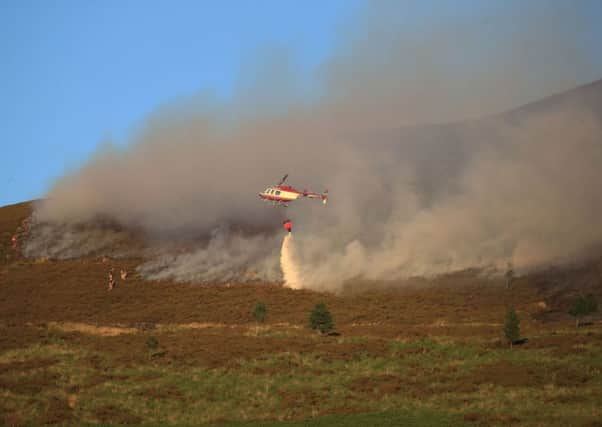 A helicopter drops water as firefighters tackle the wildfire on Saddleworth Moor. PICTURE: Peter Byrne/PA Wire
