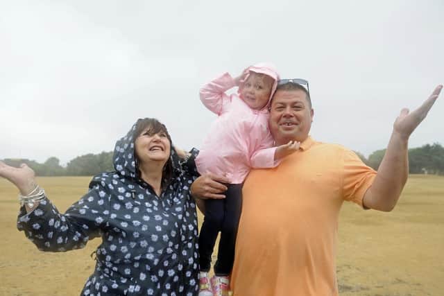 Martin and Karen Hayes from Oxfordshire with their granddaughter Ayanah Hayes, four, brave the driving rain on a wind swept Castle Field. Picture: Ian Hargreaves (180729-1)