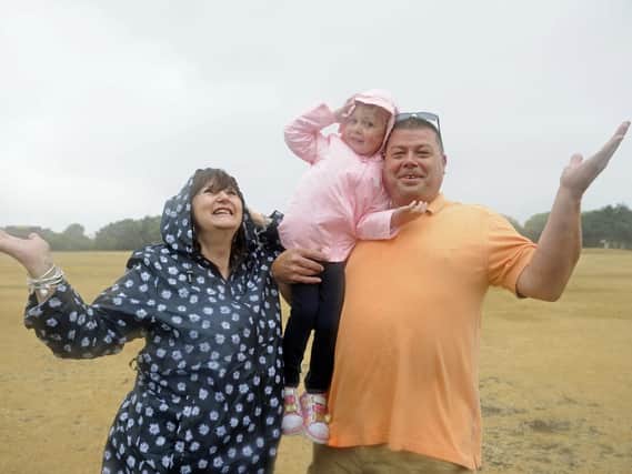 Martin and Karen Hayes from Oxfordshire with their granddaughter Ayanah Hayes, four, brave the driving rain on a wind swept Castle Field. Picture: Ian Hargreaves (180729-1)