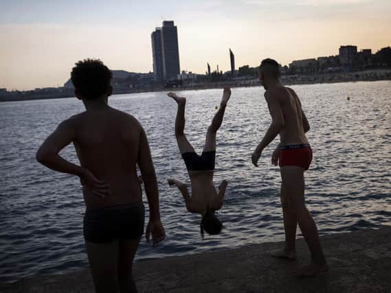 A boy jumps from a dock to the sea during a hot summer day in Barcelona, Spain. Picture: AP Photo/Emilio Morenatti