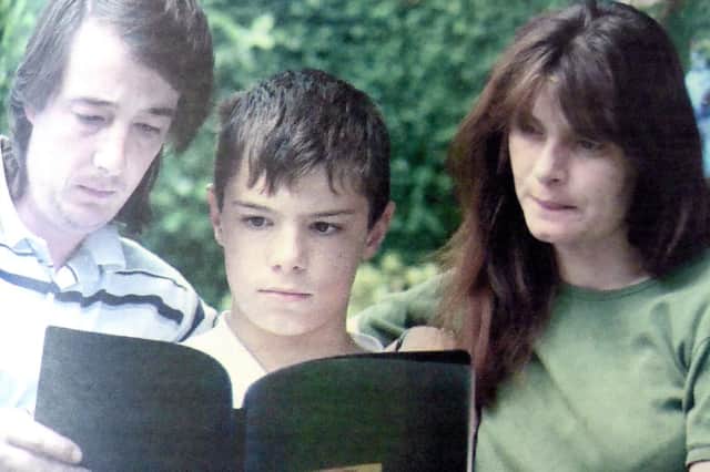 Michael and Sara Payne and their eldest son, Lee, 13, reading the book of condolence from readers of The News.