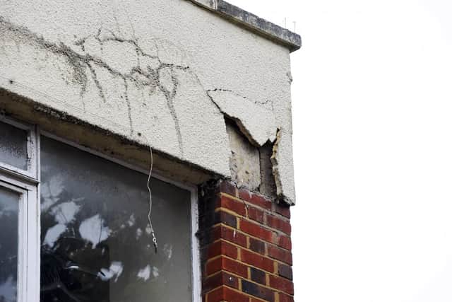 The gap left in the building's facade after the stone fell into the street