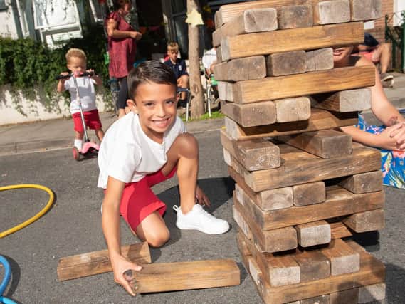FUN DAY: Street Party in Allens Road, Southsea - Riley Bridgman, nine, plays a giant game of Jenga with Che Molyneaux on a scooter behind. Picture: Vernon Nash (180429-014)