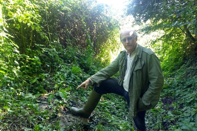 Richard Platt points to the manhole cover from which he believes the leak started