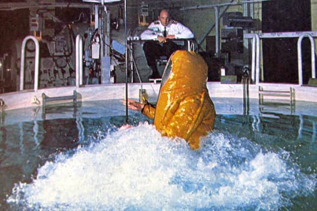 A submariner tests out the submarine escape training tower at HMS Dolphin, Gosport.