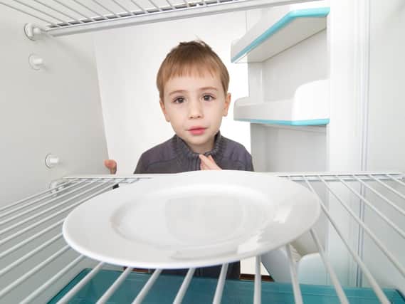 Stock image of a hungry child with no food in the fridge.