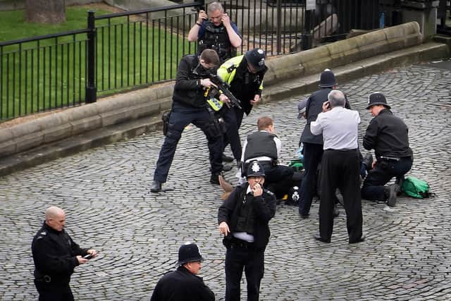 A policeman pointing a gun at Khalid Masood on the ground outside the Palace of Westminster