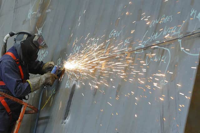 A ship builder works on a section of the first of two Queen Elizabeth class aircraft carriers at BAE Systems in Portsmouth. Picture: Chris Ison/PA Wire