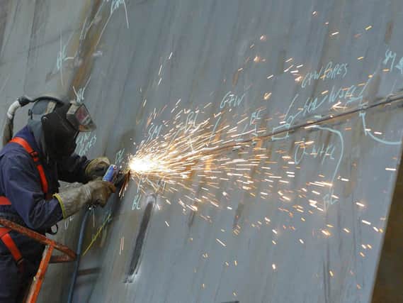 A ship builder works on a section of the first of two Queen Elizabeth class aircraft carriers at BAE Systems in Portsmouth. Picture: Chris Ison/PA Wire