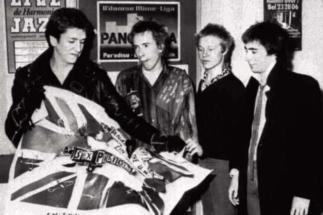 The Sex Pistols tearing an EMI poster after the announcement that they have split with their record company in 1977.