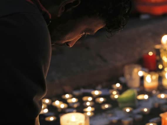 A mourner lights a candle during a vigil to commemorate victims of Friday's shooting, outside the Al Noor mosque in Christchurch, New Zealand.. (AP Photo/Vincent Yu)
