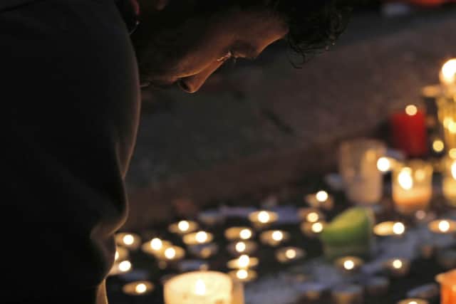 A mourner lights a candle during a vigil to commemorate victims of Friday's shooting, outside the Al Noor mosque in Christchurch, New Zealand.. (AP Photo/Vincent Yu)