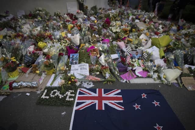 Mourners lay flowers on a wall outside the Al Noor mosque in Christchurch, New Zealand, Monday, March 18, 2019. Three days after Friday's attack, New Zealand's deadliest shooting in modern history, relatives were anxiously waiting for word on when they can bury their loved ones. (AP Photo/Vincent Thian)