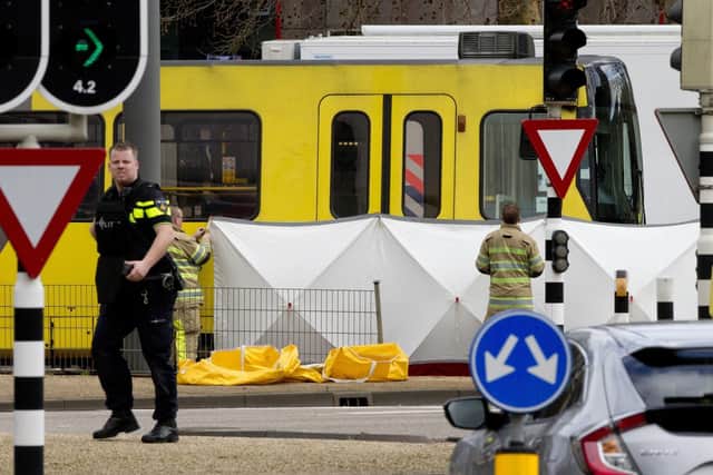 Rescue workers install a screen on the spot where a body was covered with a white blanket following a shooting in Utrecht, Netherlands, Monday, March 18, 2019. Police in the central Dutch city of Utrecht say on Twitter that "multiple" people have been injured as a result of a shooting in a tram in a residential neighborhood. (AP Photo/Peter Dejong)
