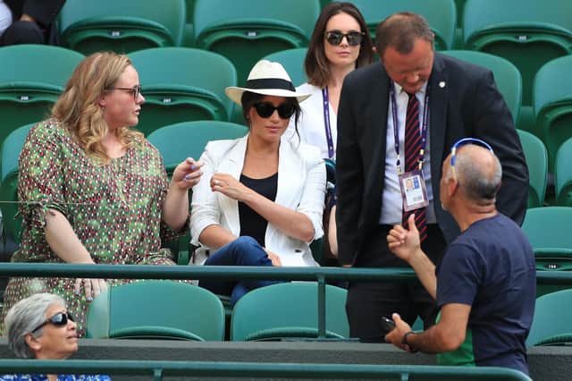 A man, believed to be a royal bodyguard, speaking to a spectator who had taken a selfie as the Duchess of Sussex watches the Serena Williams match on court one during day four of the Wimbledon Championships at the All England Lawn Tennis and Croquet Club, Wimbledon