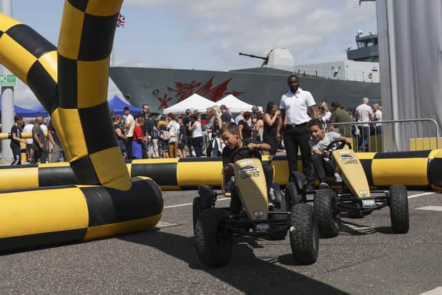 Pictured: Frankie Watson and brothers, Luca and Leo Alford compete in a race activity set up in front of HMS Dragon. Photo: LPhot Unaisi Luke
