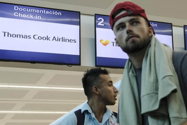 A tourist walks in front of Thomas Cook counter desk at the Cancun airport, in Mexico, Monday, Sept. 23, 2019. British tour company Thomas Cook collapsed early Monday after failing to secure emergency funding, leaving tens of thousands of vacationers stranded abroad. (AP Photo/Victor Ruiz)