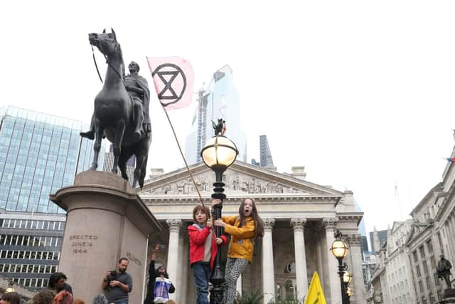 Young protesters standing on a lamp post, right of the statue of the Duke of Wellington, in front of The Royal Exchange, London, during an Extinction Rebellion (XR) climate change protest. PA Photo. Picture date: Monday October 14, 2019. See PA story ENVIRONMENT Protests. Photo credit should read: Jonathan Brady/PA Wire