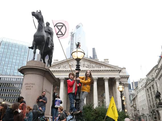 Young protesters standing on a lamp post, right of the statue of the Duke of Wellington, in front of The Royal Exchange, London, during an Extinction Rebellion (XR) climate change protest. PA Photo. Picture date: Monday October 14, 2019. See PA story ENVIRONMENT Protests. Photo credit should read: Jonathan Brady/PA Wire