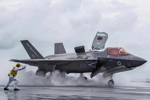 One of HMS Queen Elizabeth's flight deck officers Lieutenant Dave Robson launches the first ever UK F-35 from the supercarrier's black top. Photo: LPhot Kyle Heller.