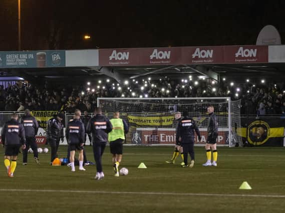 Harrogate Town fans hold their phones up as torches as the power goes out at Wetherby Road  Picture: Daniel Chesterton