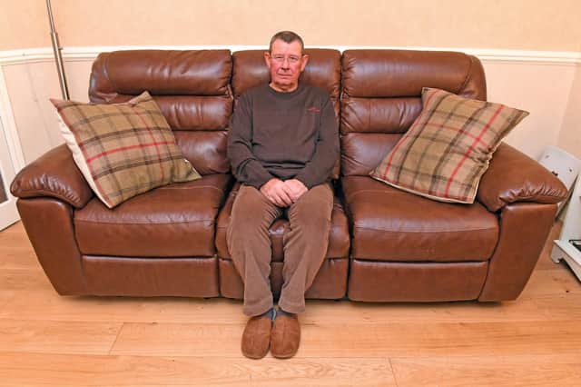 Graham Freake with the Oak Furnitureland leather settee 
Picture: Malcolm Wells (301019-9255)