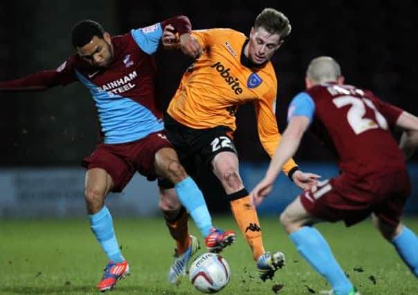 Pompey defender Adam Webster, centre, tries his hardest to stop Andy Barcham during their match-up at Glanford Park in February Picture: Joe Pepler