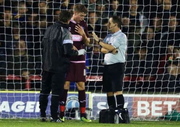 Ryan Bird is assessed by Steve Allen, left, after he was knocked out. Picture: Joe Pepler