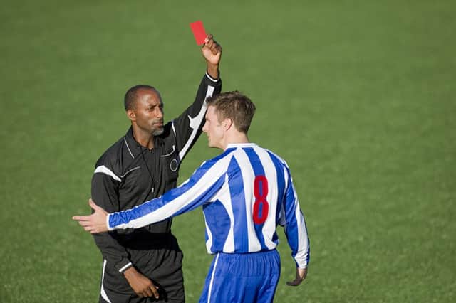 Soccer player receiving a red card from the match referee. A new study has found that football referees dont suffer as much criticism as they believe