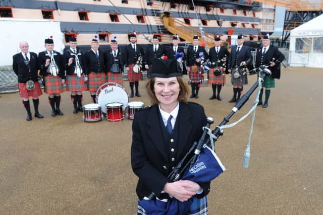 Piper Irene Robinson plays her bagpipes at HMS Victory as part of her challenge