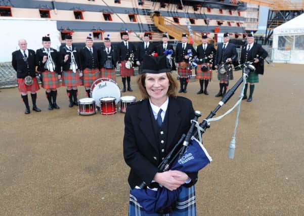 Piper Irene Robinson plays her bagpipes at HMS Victory as part of her challenge