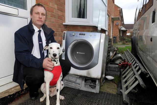 Taxi driver John Wood with his dog Rosie, next to the tumble dryer which he claims caused a fire that killed his other dog Holly