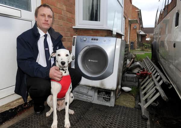 Taxi driver John Wood with his dog Rosie, next to the tumble dryer which he claims caused a fire that killed his other dog Holly