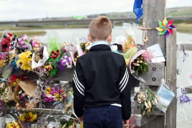 Child stares at tributes left to the victims of the Shoreham Airshow disaster
