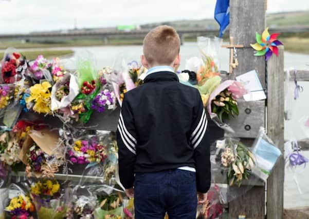 Child stares at tributes left to the victims of the Shoreham Airshow disaster