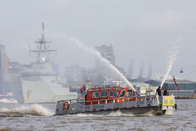 Fire Dart firing its hoses in front of HMS Severn as she approaches London