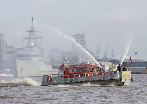 Fire Dart firing its hoses in front of HMS Severn as she approaches London