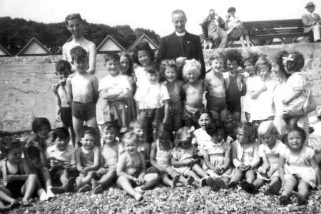 Cecilia Vaughan with fellow Montessori pupils enoying a trip to the beach. The chaplain was James Larkin and the school's founder, Marian Matthews, is on the right holding the girl with a ribbon in her hair