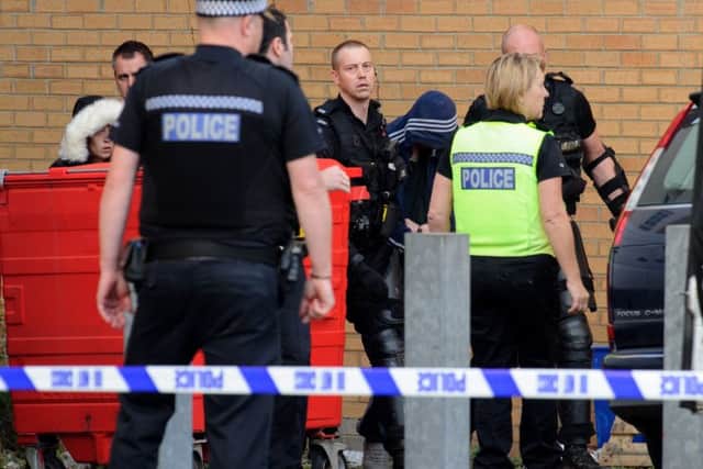 Police lead Tobias Maylott in a hooded top from the rear entrance to Virgin Media store in Commercial Road.