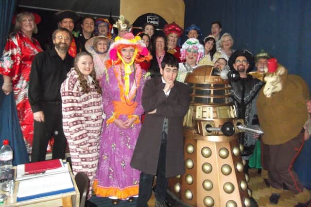 The cast of Aladdin by Curtain Up! Productions pose with the fundraising Dalek