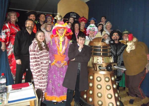 The cast of Aladdin by Curtain Up! Productions pose with the fundraising Dalek