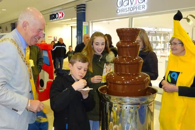 Young shoppers enjoy the taste of luscious Fairtrade chocolate, watched by Mayor of Fareham Cllr Mike Ford and Fairtrade Borough group member Jane Tredgett