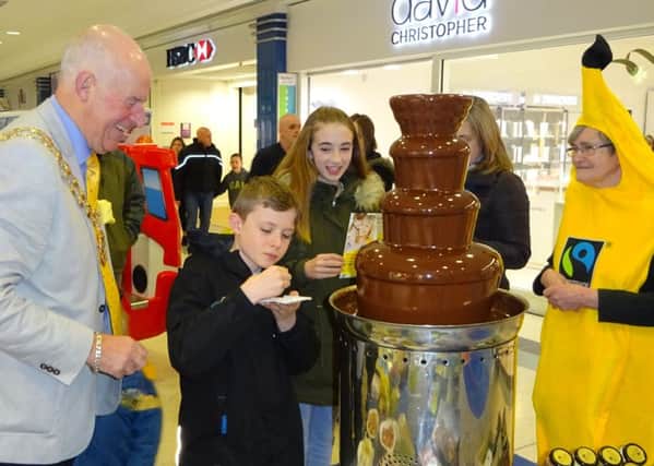 Young shoppers enjoy the taste of luscious Fairtrade chocolate, watched by Mayor of Fareham Cllr Mike Ford and Fairtrade Borough group member Jane Tredgett