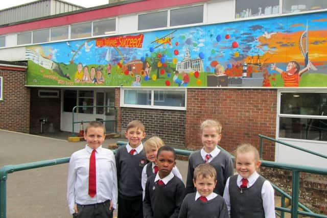An artist brings childrens ideas to life on the wall outside St Pauls Catholic School