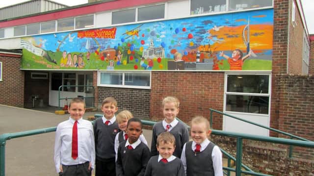 An artist brings childrens ideas to life on the wall outside St Pauls Catholic School