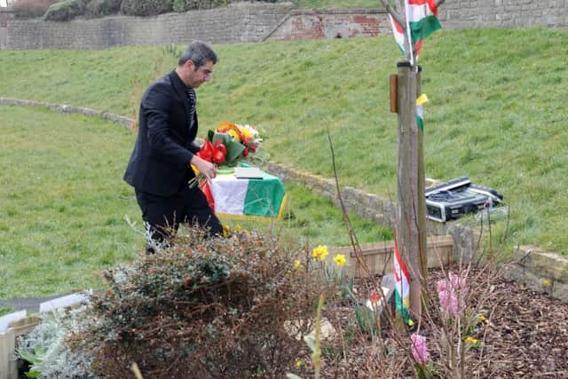 Kamaran Haider lays a bouquet of flowers in remembrance