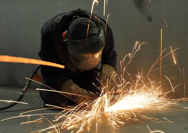 A fitter cutting steel inside the C ring of the HMS Queen Elizabeth in the shipbuilding hall at Portsmouth Dockyard