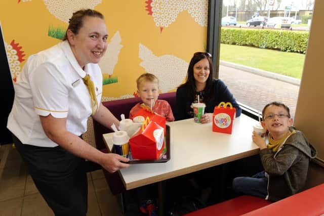 From left, admin manager Julie Norris (47), serves McDonald's customers with their order at their table (left to right) Paul Watson (5), mum Cathy Watson and Ben Watson (6) Picture by: Malcolm Wells (160331-1754)